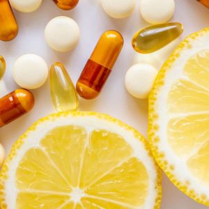 Ergänzungsmittel in Form von Kapseln und Tabletten, arrangiert um Zitronenscheiben herum, was die Wahl zwischen natürlichen Vitaminquellen und Nahrungsergänzungsmitteln symbolisiert